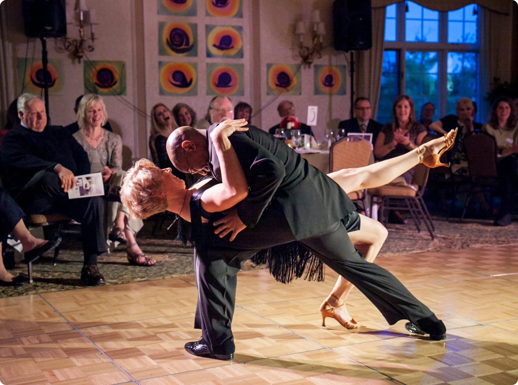 Wedding dance instructor, Dorian Deaver, dipping his dance partner, who has a big smile.