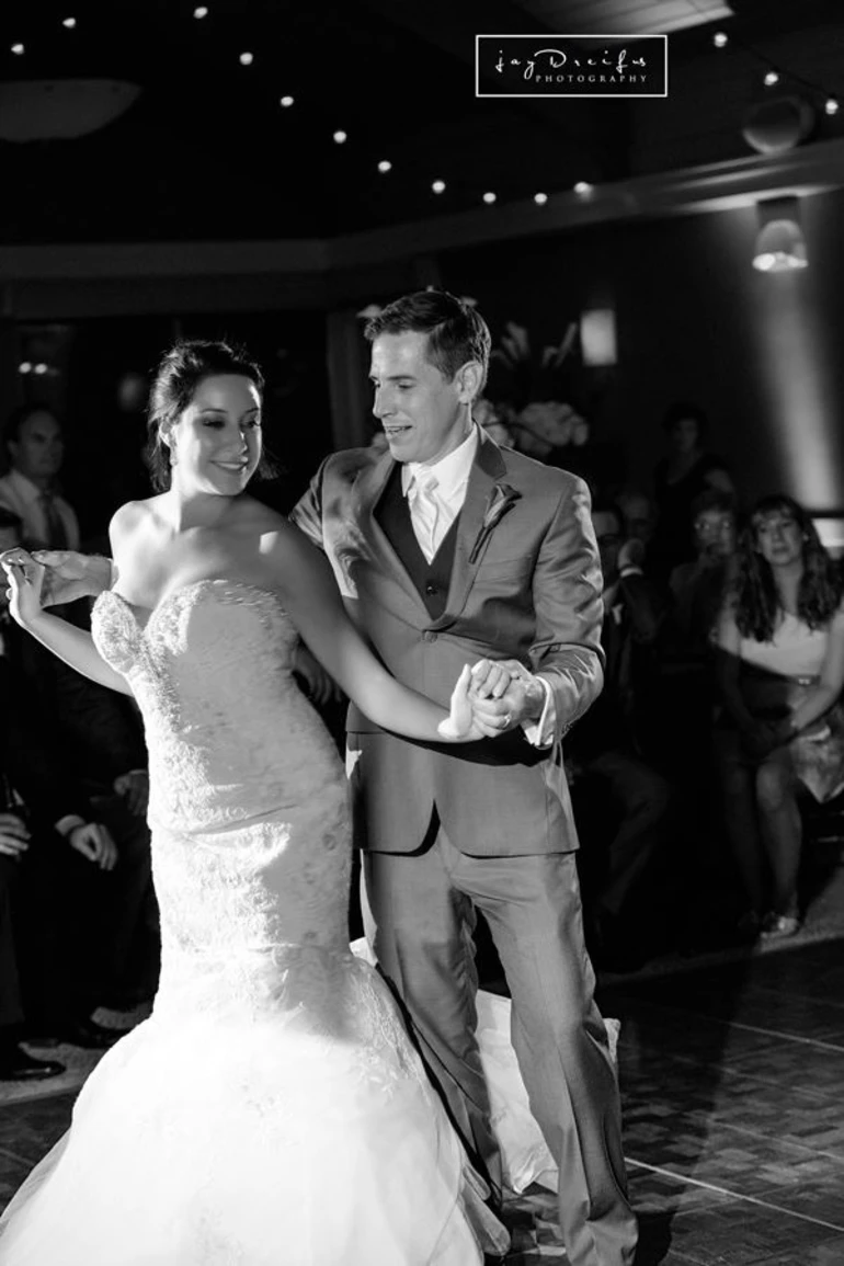 A couple dancing in wedding attire, the bride and groom are both facing the camera