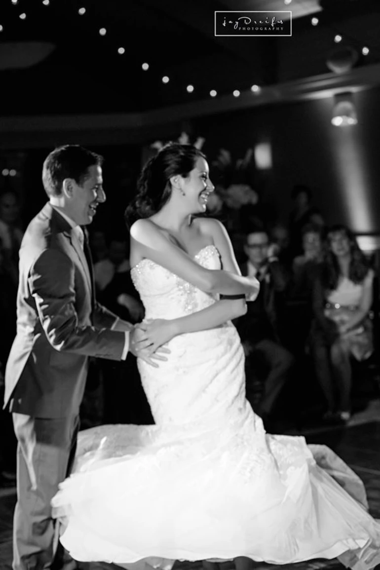 A couple dancing in wedding attire, the bride is being spun around and they both have big smiles