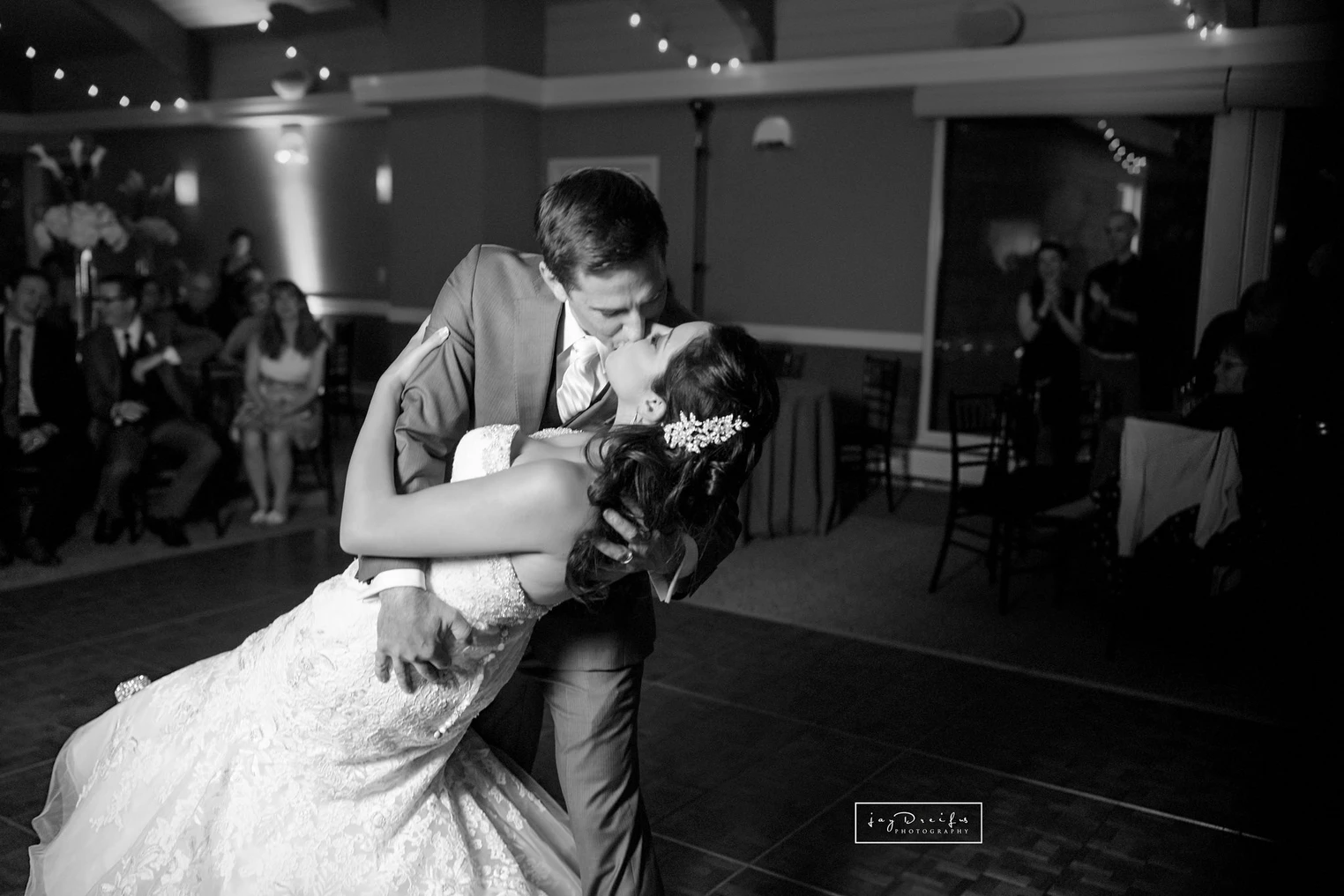 A could dancing in wedding attire, the groom is dipping the bride while they kiss